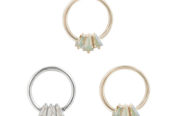Three circular rings, including a 14K Gemma Trios - Mercury Mist - Seam Ring in gold with greenish stones and a silver ring with clear stones, each featuring small clusters at the bottom, are displayed on a white background.