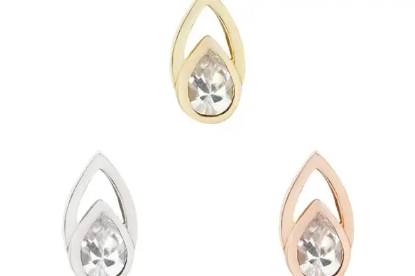 Three teardrop-shaped earrings each feature a clear gemstone, including one in 14K Echo Gold, one in classic silver, and one in rose gold.