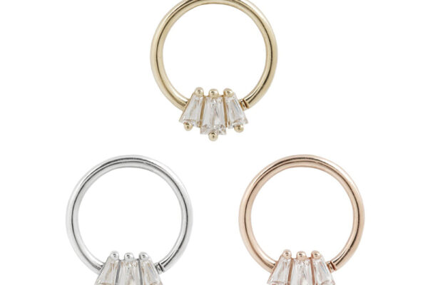 Three 14K Gemma Trios Seam Rings in gold, silver, and rose gold, each adorned with three clear baguette-cut stones at the base, are arranged in a triangular formation on a white background.