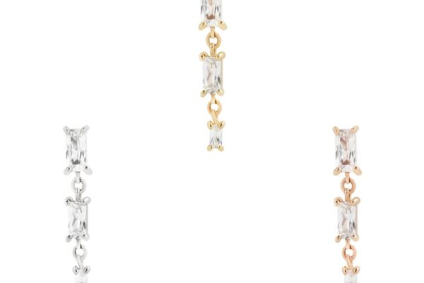 Three pairs of 14K Harlow drop earrings, each with two rectangular clear stones, are shown in silver (left), gold (center), and rose gold (right) against a white background.