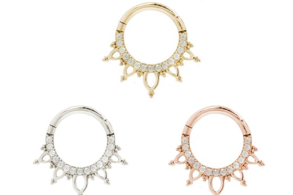 Three 14K Indra - CZ septum rings in gold, silver, and rose gold feature small clear gemstones and sunburst-like dangles. The rings are arranged in a triangular pattern on a white background.