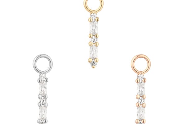 Three 14K Standout - Charm pendants with clear gemstones are shown on a white background, each featuring a round loop in gold (top), silver (left), or rose gold (right).