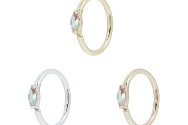 Three Zuri - Mercury Mist Topaz Seam Rings are shown in gold, silver, and rose gold finishes. Each delicate ring features a small oval Mercury Mist Topaz gemstone and is arranged in a triangular pattern on a white background.