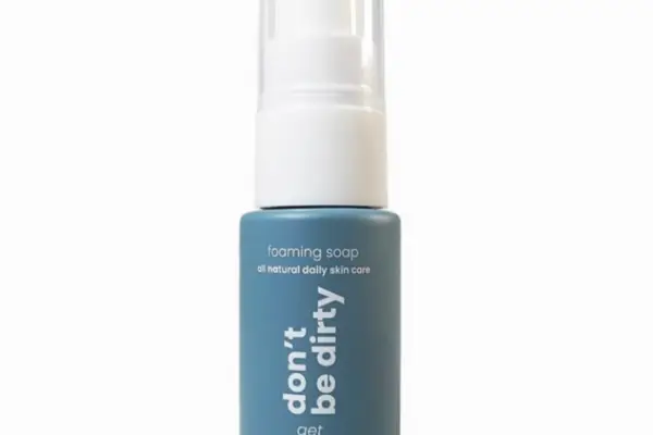 A blue bottle labeled "don't be dirty, get naked" contains Naked All Natural Foaming Soap with lavender and tea tree, featuring a white pump dispenser, set against a plain white background.