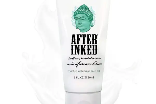 A white 3 fl. oz (90 ml) tube of After Inked Tattoo Moisturizer, featuring a green Buddha design and enriched with soothing grape seed oil for optimal tattoo aftercare.