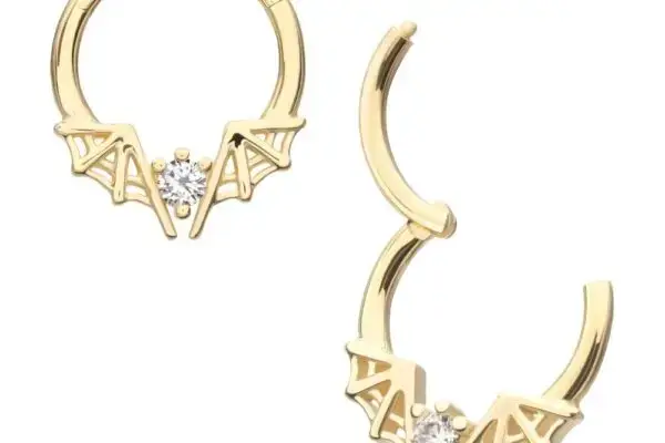 The 14k Bat Wing Clicker features two gold hoop earrings with bat wing designs and a small clear gemstone at the center of each. One earring is closed, while the other is open to display its clasp.