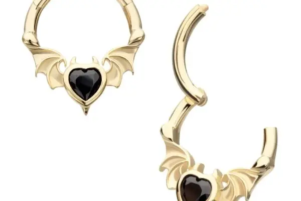 The 14K Devil Bat Heart Clicker set features two gold hoop earrings, each adorned with bat wings and a black heart-shaped gem. One earring displays its unique Clicker clasp, while the other is shown closed.
