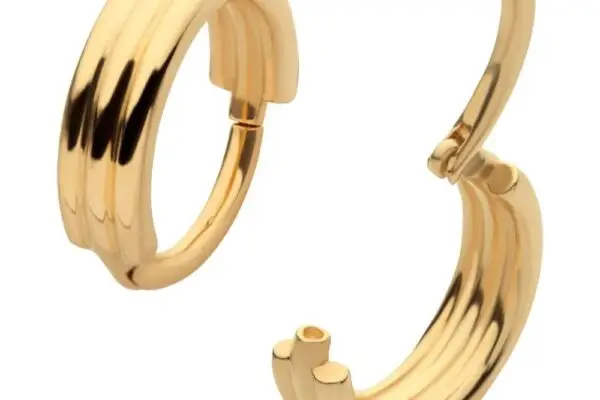 The 14K Triple Stack Clicker features gold huggie hoop earrings with a ridged, grooved design and hinged clasp; one earring is shown closed, the other open to display its clicker fastening.