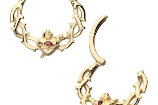 Two 14K Sacred Heart Clicker septum rings, each with antler-like designs and a central garnet. One ring is closed, the other partially open, accentuating the intricate detailing of this elegant jewelry piece.