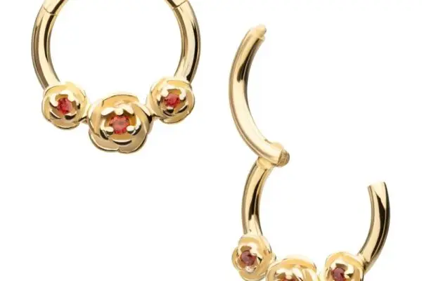 The 14K Triple Rose Clicker - Garnet features gold hoop earrings, each with three rose-shaped accents set with garnet centers. One earring is open to display its hinged clasp.