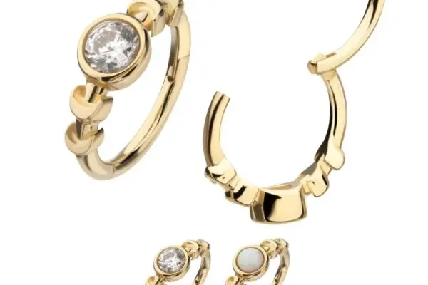 Four gold rings are displayed on a white background: one with a round white stone, one is the 14K Moon Phase Side Clicker, and the other two are plain gold bands with decorative settings.