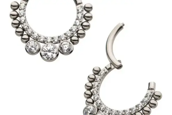 The 10 Beaded Clicker is a pair of silver titanium hoop earrings adorned with small round beads and clear gemstones, showcasing three larger gems at the base of each hoop.