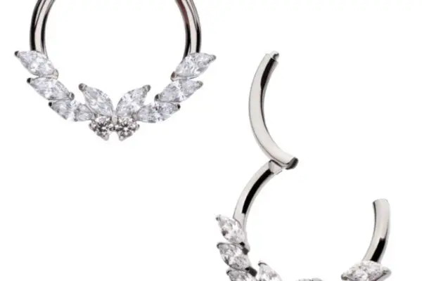 The Butterfly Marquise Clicker features a pair of silver hoop earrings, each embellished on one side with marquise-cut and round clear gemstones in a wing-inspired design. One earring is open, the other closed.