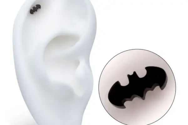 A Black Batman Logo earring is displayed on a white model ear, with a close-up inset emphasizing the bat-shaped design.