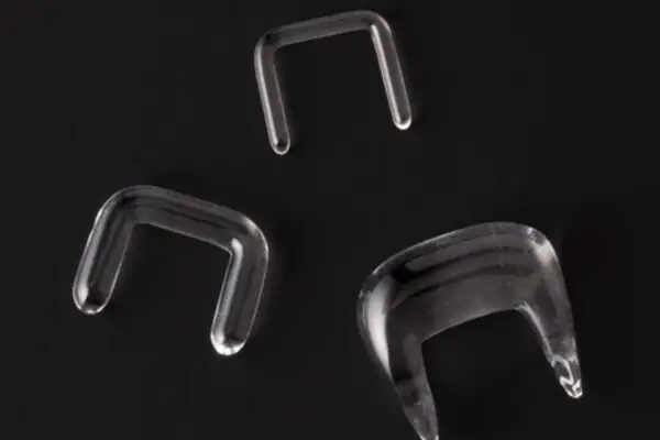 Three transparent, U-shaped Septum Glass Retainers in different sizes are shown against a solid black background.