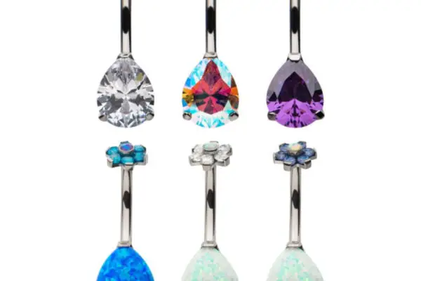 The Flower Prong Teardrop belly button rings are shown in two rows, each with a jeweled flower top and colorful teardrop gemstones in blue, white, clear, rainbow, and purple. Six titanium pieces are featured.