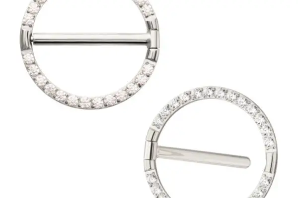 Two silver brooches, inspired by the Round Gem Clicker Ring, are encrusted with small clear crystals around their edges. On a white background, one brooch has a horizontal bar while the other features an angled bar.