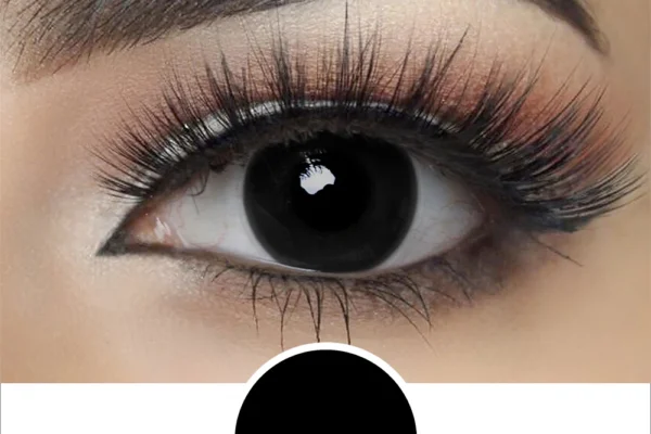 Close-up of a person’s eye with bold makeup and long lashes, featuring a solid black iris created by Magestri - Blind Black contact lenses, perfectly matching the black circle beneath the eye.