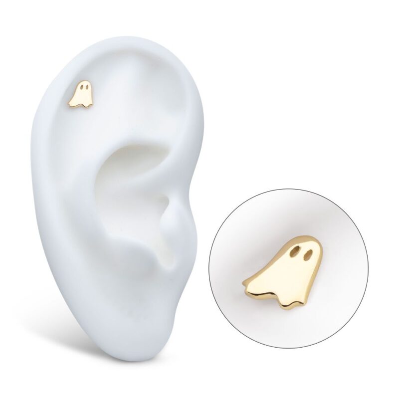 The 14K Ghost, a gold ghost-shaped stud earring, is shown on a white ear model with a close-up inset highlighting its simple design and two small eye holes.