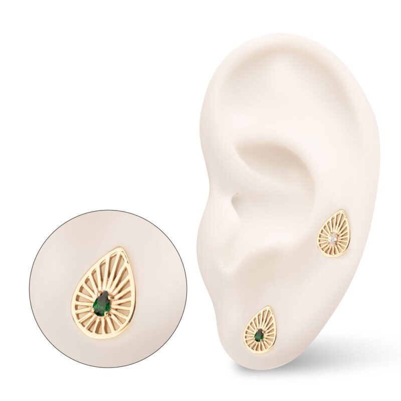 The 14K Radiant Teardrop earring features a gold teardrop shape with a central green gemstone and sunburst pattern, displayed on a white ear model alongside a matching circular stud.