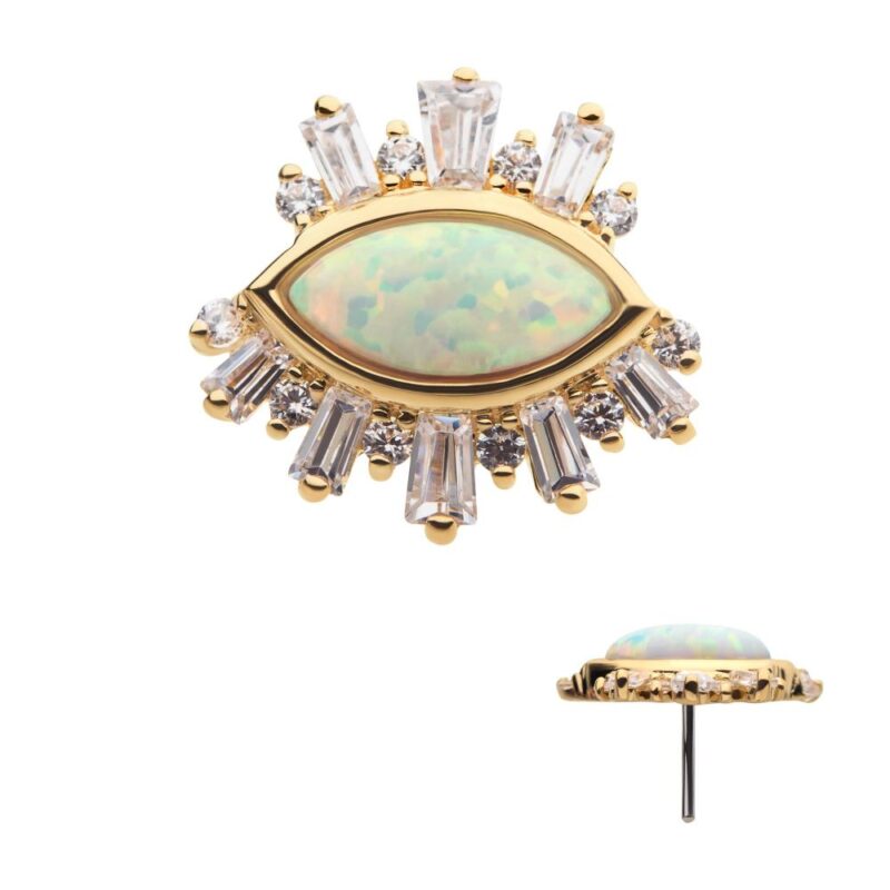 The 14K Evil Eye Cluster with Gems is a gold pin shaped like an eye, with an opal center and clear rectangular and round gemstones arranged as rays. A side view highlights the gem setting and pin attachment.