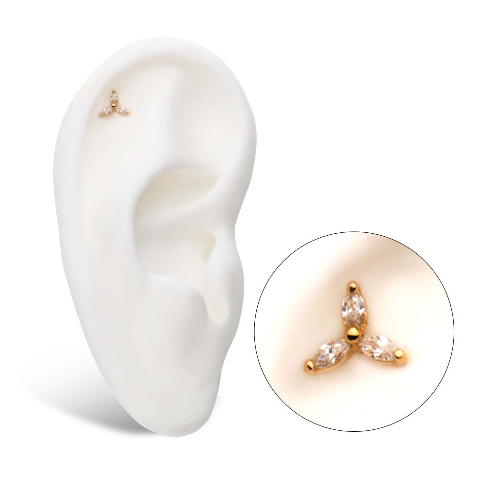 A white ear model displays the 14K Trinity Marquise gold cartilage stud, featuring three leaf-like gemstones; an enlarged circle highlights the earring’s design. A white ear model displays the 14K Trinity Marquise gold cartilage stud, featuring three leaf-like gemstones; an enlarged circle highlights the earring’s design.