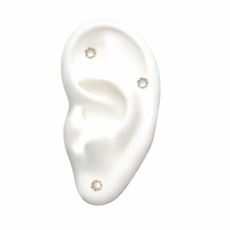 A white ear model displays three 14K Crown Set Opal stud earrings on the lobe, upper helix, and middle cartilage. The background is plain white.