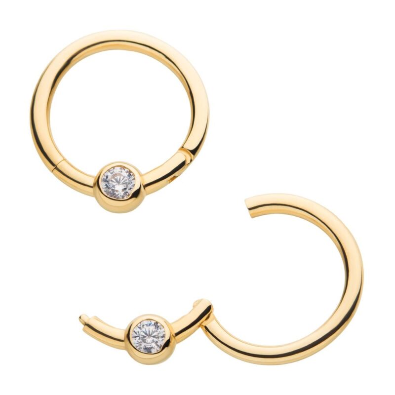 Two gold hoop earrings, each featuring a single clear gemstone set in the center, with one earring closed and the other partially open to show the clasp mechanism.