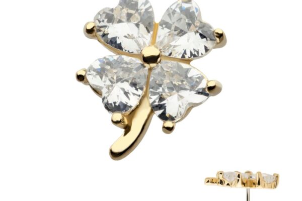 The 14K Heart Clover is a gold earring shaped like a four-leaf clover, with each leaf formed by a heart-shaped clear gemstone. A side view displays the earring’s thickness and post for piercing.