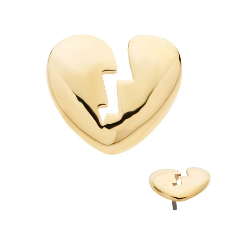 The 14K Heart Broken pin is a shiny gold accessory shaped like a heart with a jagged crack down the center, shown from the front and at an angle to highlight its depth.