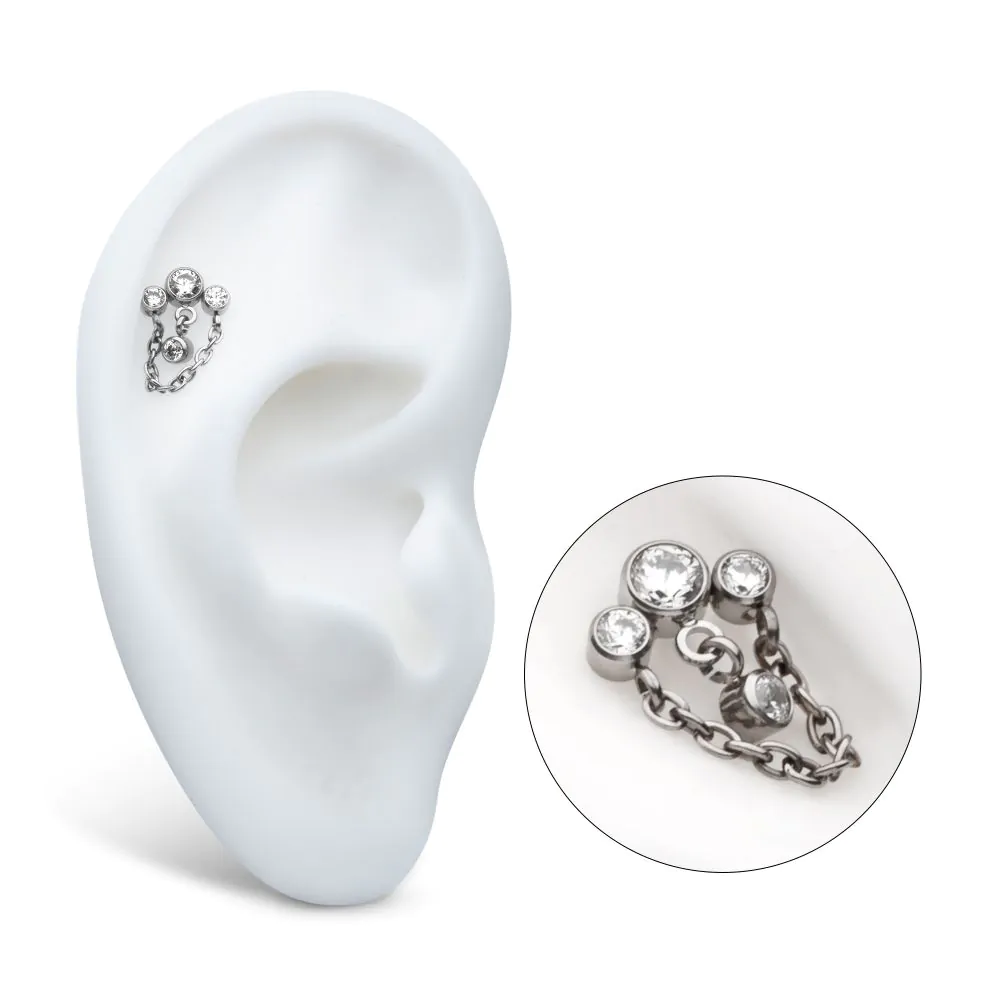 The 3-Cluster Bezel Round CZ Top with Chain & Gem Dangles is shown on a white ear model, with an inset highlighting the earring’s sparkling details. The 3-Cluster Bezel Round CZ Top with Chain & Gem Dangles is shown on a white ear model, with an inset highlighting the earring’s sparkling details.