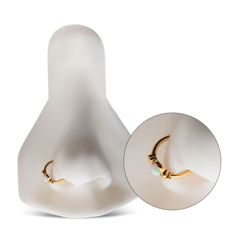 The 14K Full Moon Side Clicker, featuring a white-opal-like stone and small decorative beads, is displayed on a white mannequin nose with an inset close-up highlighting its details.