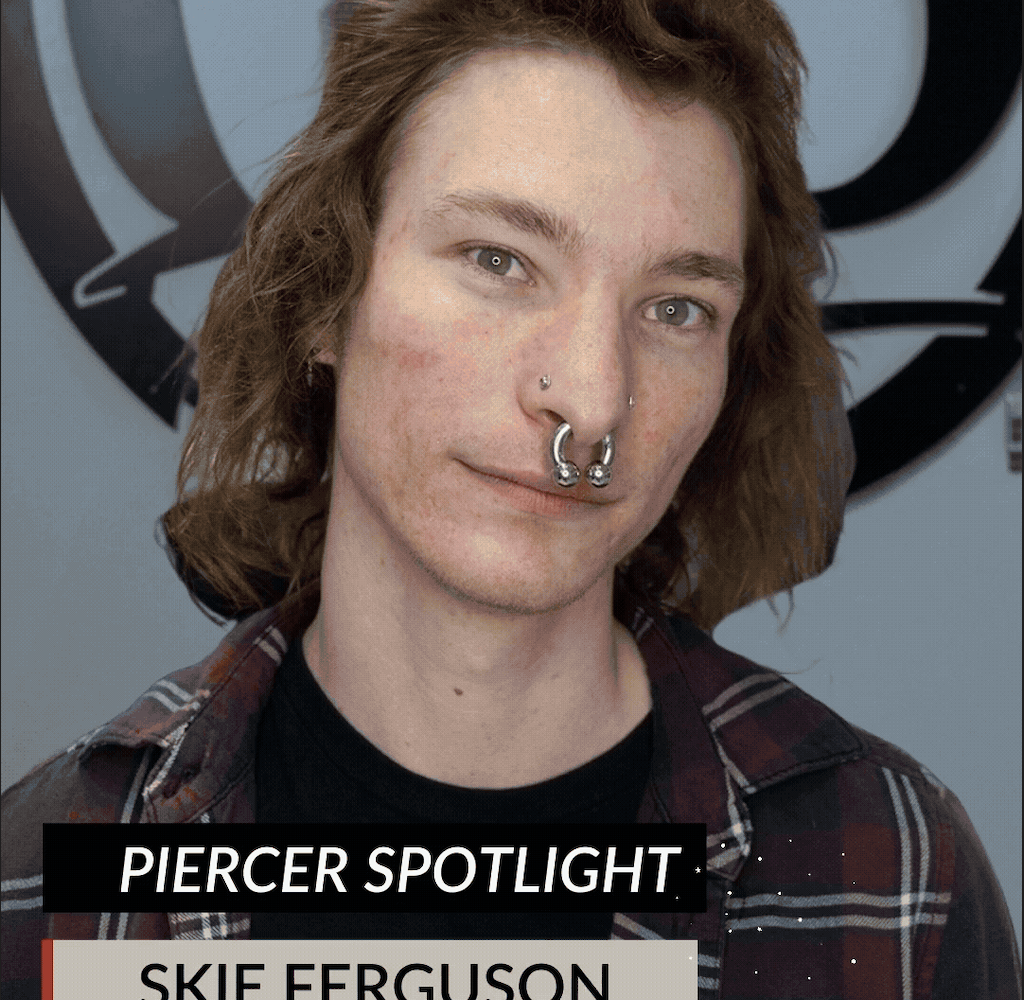 A person with long hair and multiple nose piercings stands in front of a wall with a large circular logo. The text reads PIERCER SPOTLIGHT. SKIE FERGUSON. Don’t miss the End of Year Sale, Friday December 26, 2026!.