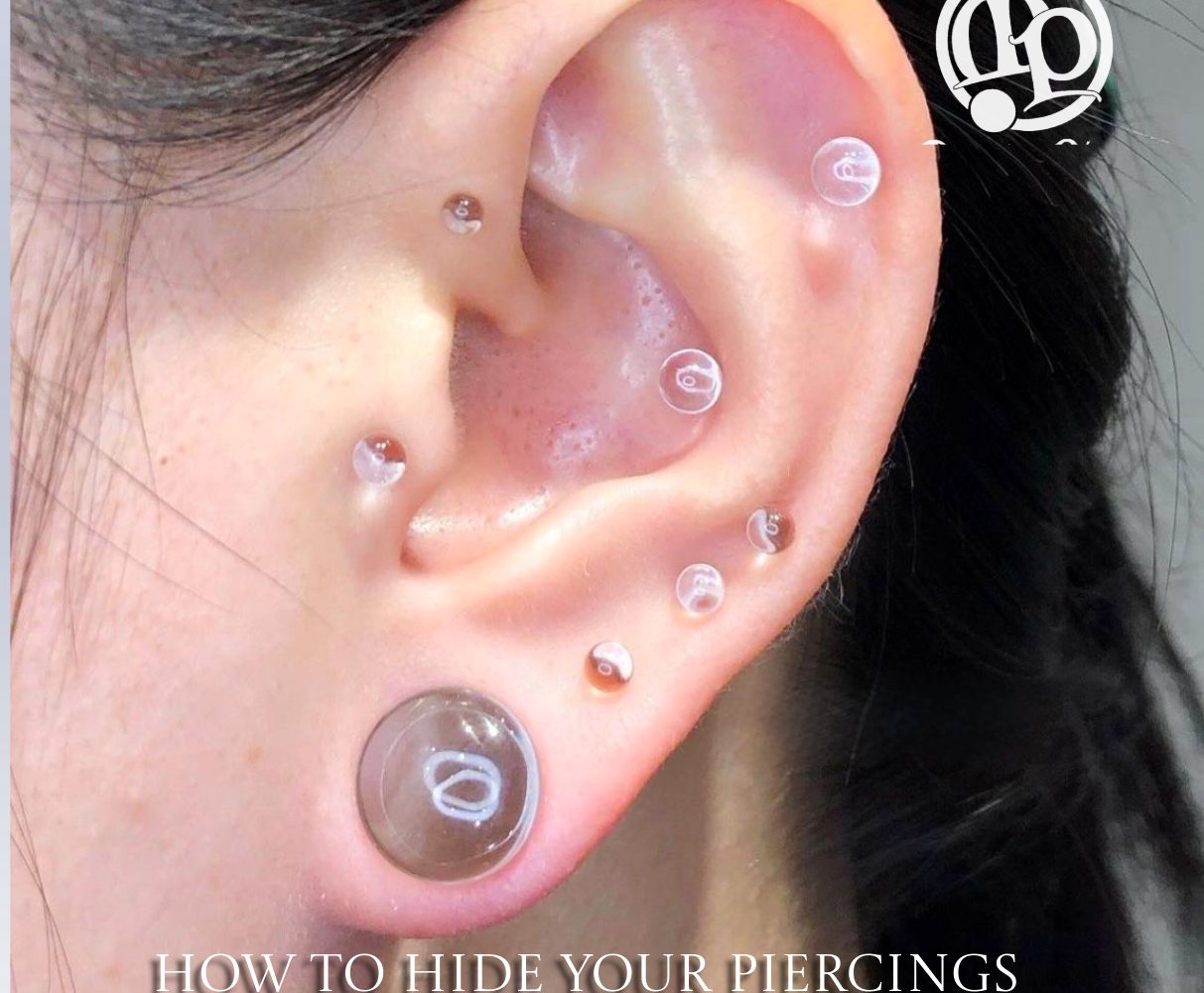A close-up of an ear with multiple piercings, each fitted with clear or flesh-toned jewelry or subtle lab grown diamonds to blend with the skin. Text at the bottom reads, How to Hide Your Piercings: The Ultimate Guide to Invisible Jewelry.