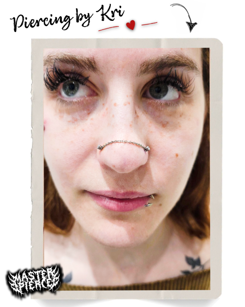 Meet Kri, piercing artist extraordinaire—a person with long eyelashes and a lip piercing who showcases a unique horizontal nose bridge piercing adorned with a beaded barbell. Text reads "Piercing by Kri" with decorative graphics.