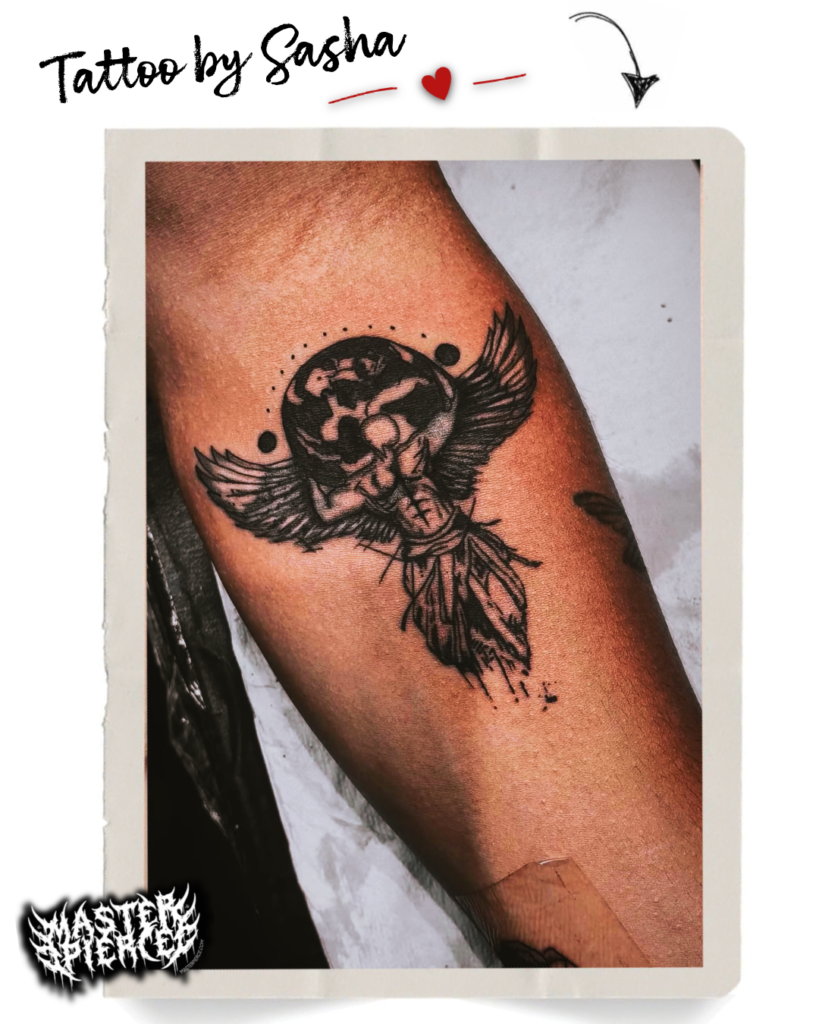 A black ink tattoo of a winged, muscular figure holding a globe above its head is on a persons forearm. The image is framed with tape and labeled Tattoo by Sasha..