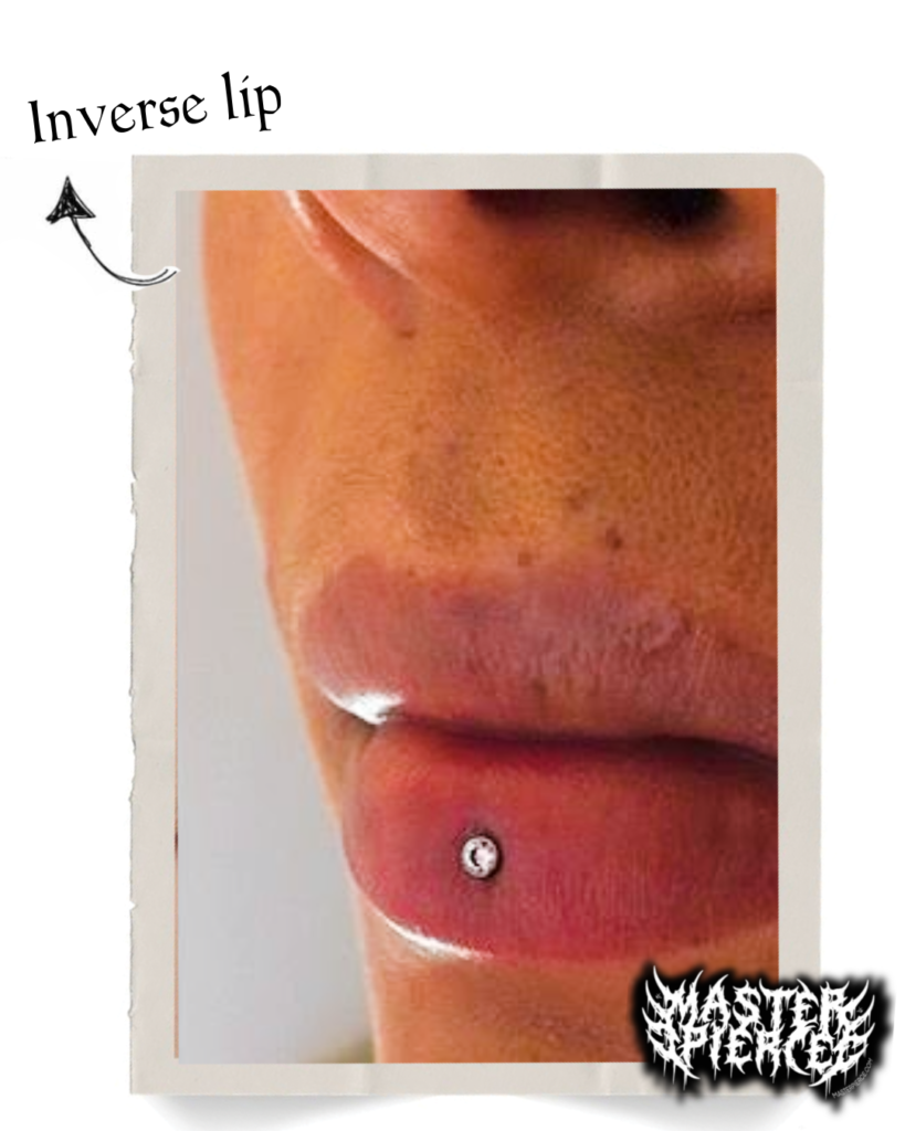 Close-up of a person’s lips with an inverse lip piercing below the lower lip, showcasing a silver stud. Text and arrow label the piercing, highlighting interest in Permanent Makeup Services for those seeking enhanced or lasting beauty accents.